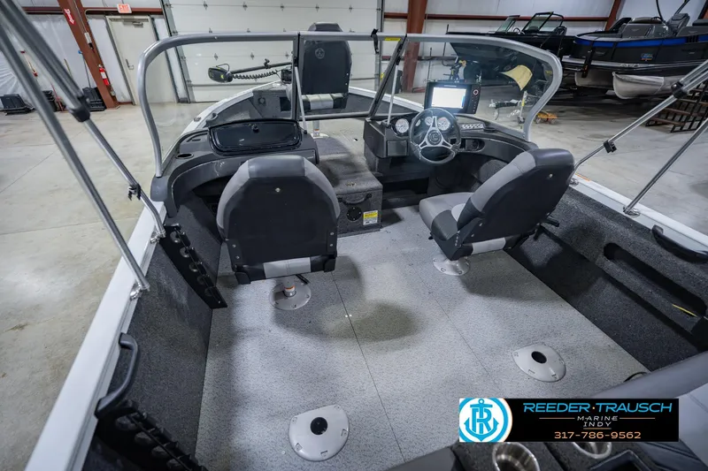Slide: The Image of 2014 Crestliner 1650 Fish Hawk SE interior with dual seats and steering console in a showroom. - 15