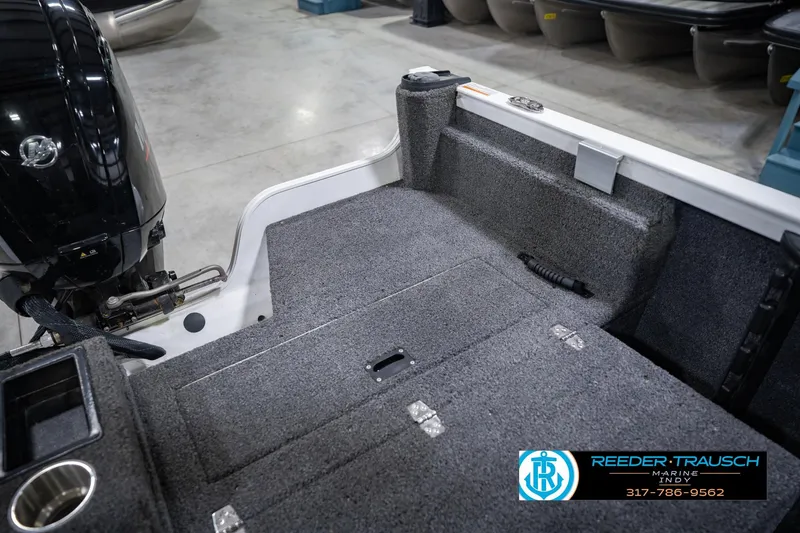 Slide: The Image of 2014 Crestliner 1650 Fish Hawk SE boat interior with motor, carpeted deck, and storage compartments. - 24