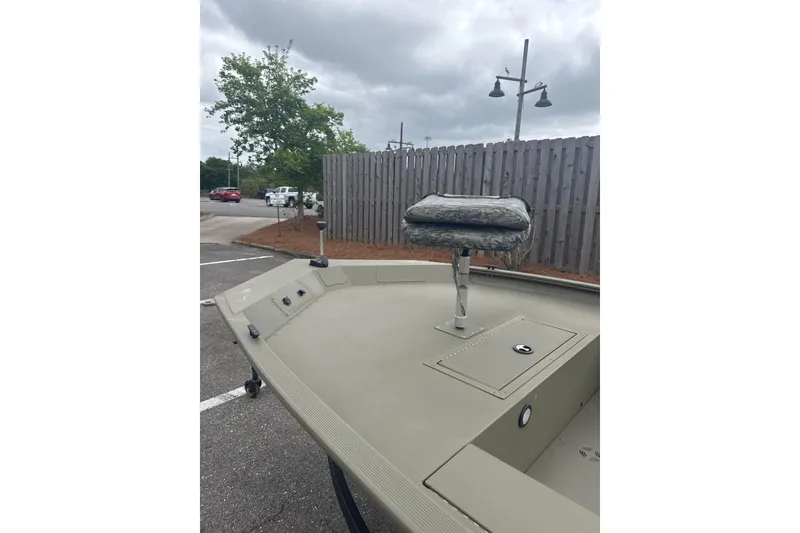 Slide: The Image of 2026 Tracker Grizzly 1654 T Sportsman boat with camo seat, parked outdoors. - 4