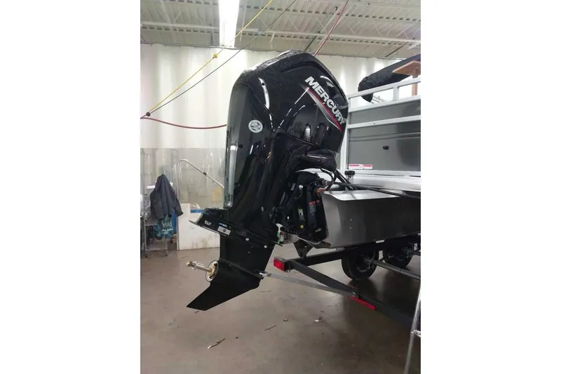 Slide: The Image of 2026 Sun Tracker Fishin' Barge 20 DLX with Mercury outboard motor in a workshop. - 99