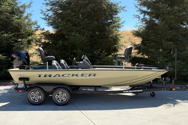 The Image of 2026 Tracker Pro Team 195 boat on trailer, parked outdoors near trees. - 0