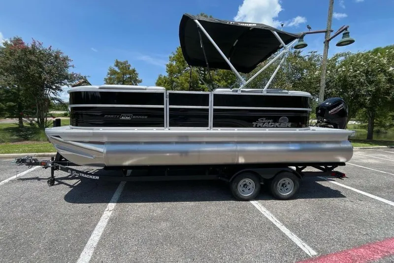 The Image of 2026 Sun Tracker Party Barge 20 DLX pontoon boat on trailer in parking lot. - 0