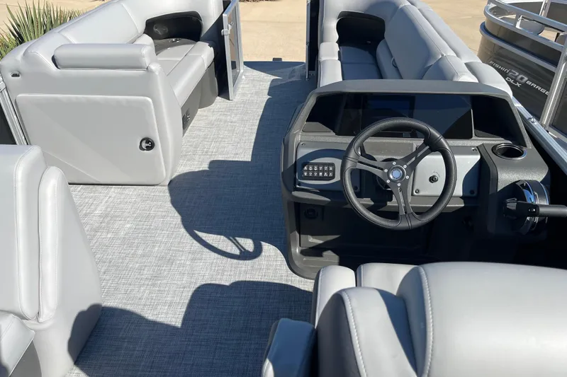 Slide: The Image of 2026 Sun Tracker Party Barge 20 DLX interior with gray seating and steering console. - 2