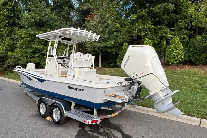 Slide: The Image of 2026 Ranger 2510 Bay boat with Mercury outboard engine on a trailer, parked outdoors. - 4