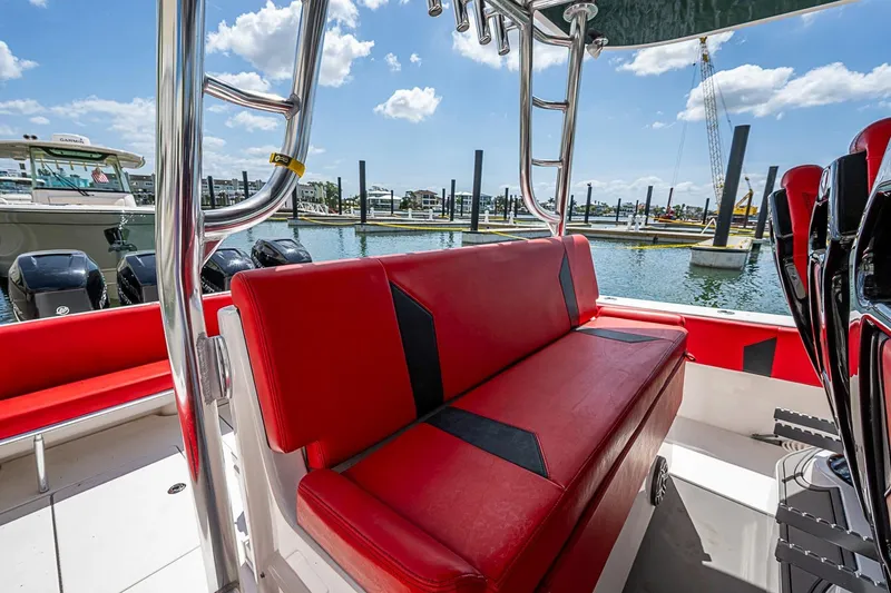 Slide: The Image of 2021 Contender 44 ST boat with red seating, docked at a marina under a clear sky. - 32