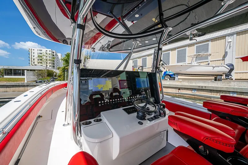 Slide: The Image of 2021 Contender 44 ST boat with red seating, docked at a marina under a clear sky. - 34