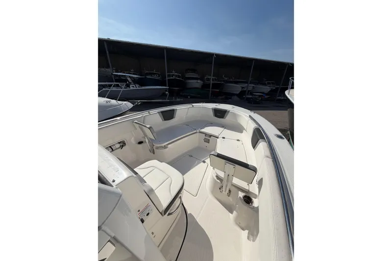 Slide: The Image of 2024 Robalo R250 Center Console boat interior with seating and storage, docked in a marina. - 16
