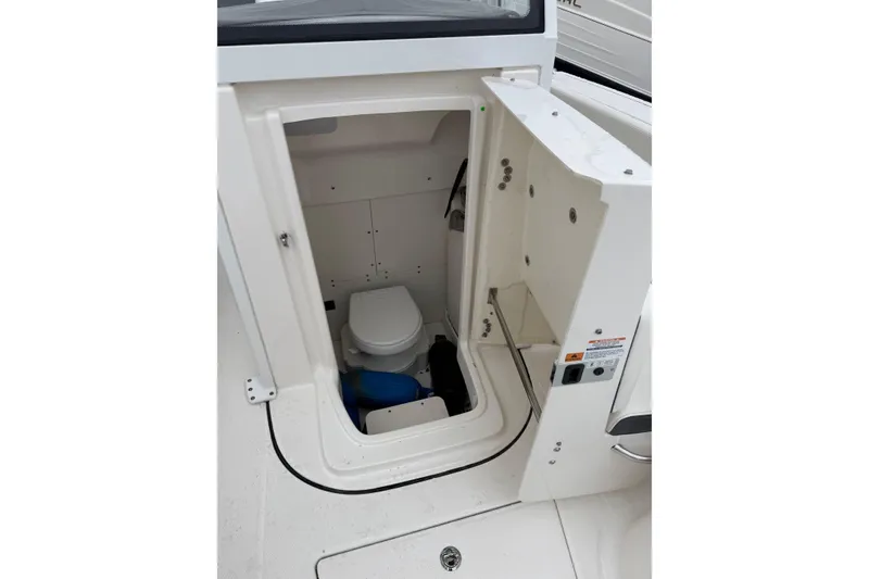 Slide: The Image of 2024 Robalo R250 Center Console boat interior with compact marine toilet. - 18