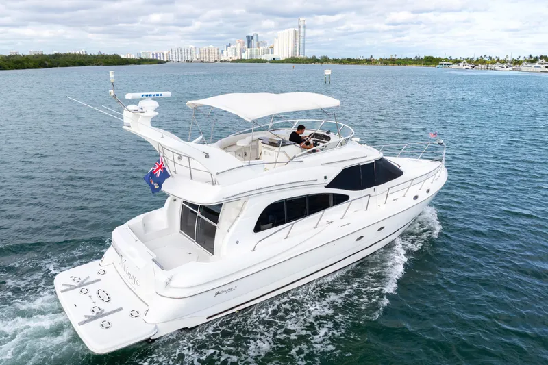 The Image of 2001 Cruisers Yachts 5000 Sedan Sport cruising on open water with city skyline backdrop. - 0