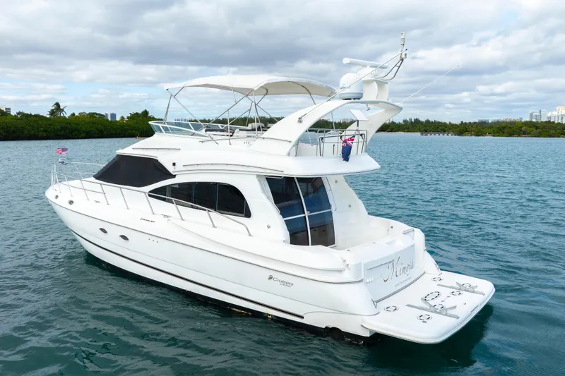 Slide: The Image of 2001 Cruisers Yachts 5000 Sedan Sport on serene water, showcasing elegant design and spacious deck. - 16