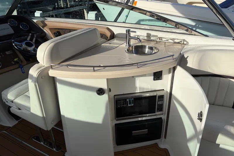 Slide: The Image of Interior of a 2015 Cobalt 336 boat featuring a compact kitchenette with sink and seating. - 19