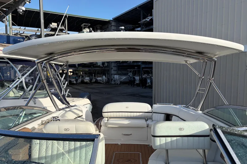Slide: The Image of 2015 Cobalt 336 boat interior with white seating and sleek design in a marina setting. - 32