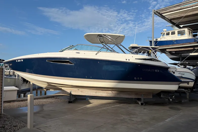 Slide: The Image of 2015 Cobalt 336 boat in dry dock, featuring sleek blue and white design. - 4