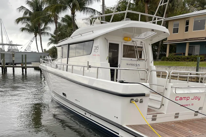 Slide: The Image of Sargo 36 Flybridge 2015 yacht docked near palm trees and waterfront homes. - 2