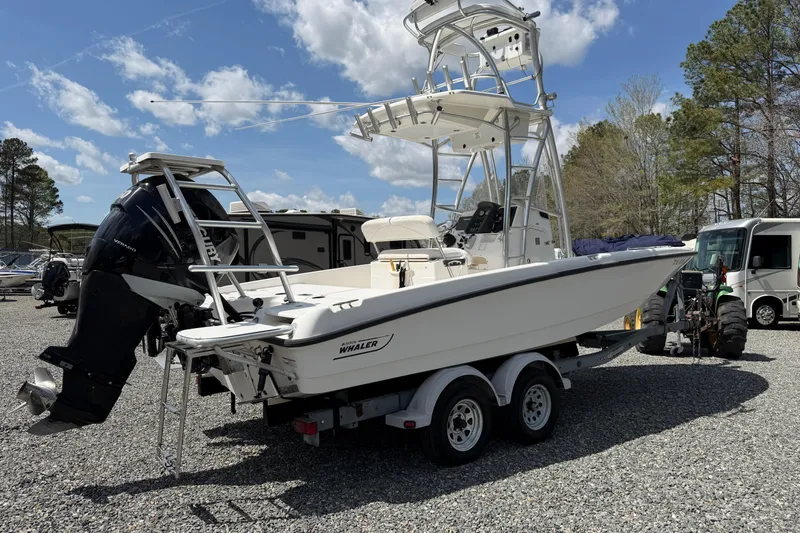 Slide: The Image of 2009 Boston Whaler 230 Dauntless boat on trailer, parked outdoors under blue sky. - 2