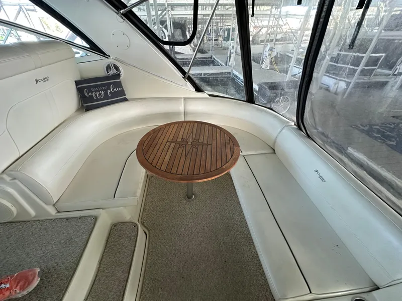 Slide: The Image of 2005 Cruisers Yachts 340 Express interior with curved seating and wooden table. - 2
