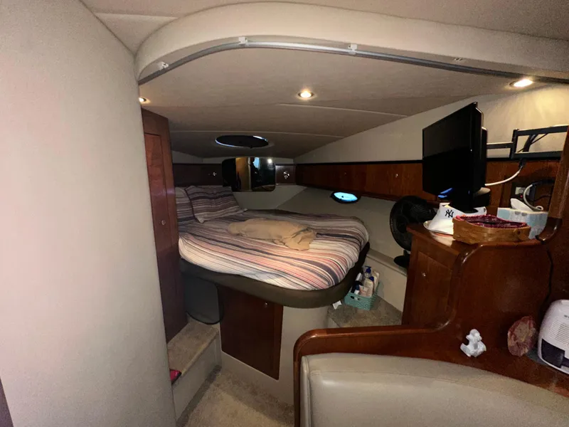 Slide: The Image of 2005 Cruisers Yachts 340 Express cabin interior with bed, TV, and wooden cabinetry. - 7