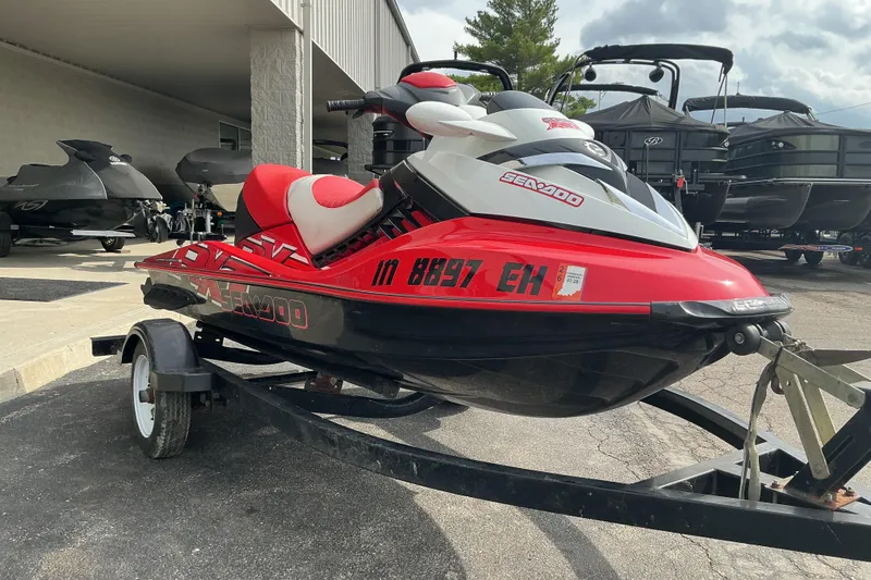 The Image of 2007 Sea-Doo RXT 215 jet ski on trailer, red and white design, parked outdoors. - 1