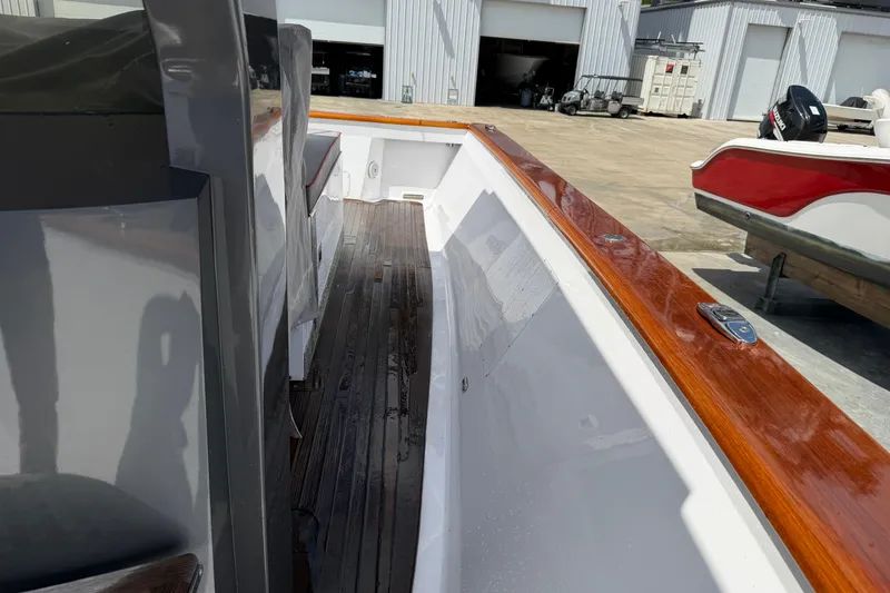 Slide: The Image of Custom 2013 Jet Center Console boat with wooden trim and sleek design in a marina setting. - 12