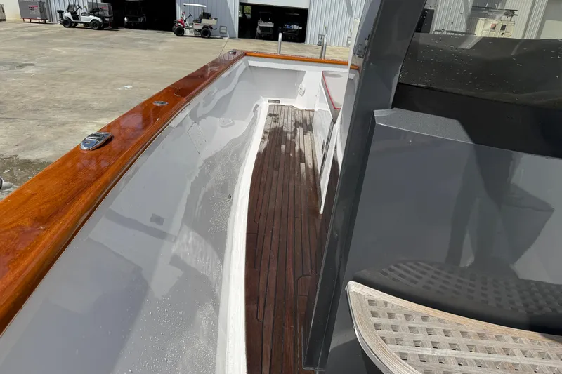 Slide: The Image of Custom 2013 Jet Center Console boat with wooden deck and sleek design in a marina setting. - 13