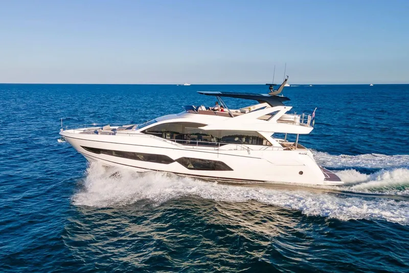 The Image of Luxurious 2022 Sunseeker 76 Yacht cruising on open sea under clear blue sky. - 1