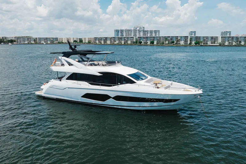 Slide: The Image of Luxurious 2022 Sunseeker 76 Yacht cruising on serene waters, cityscape in background. - 5