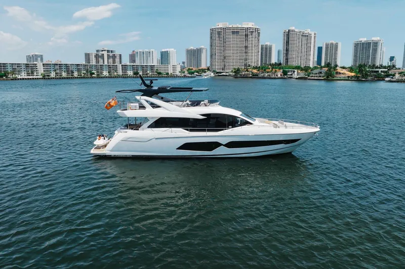 Slide: The Image of 2022 Sunseeker 76 Yacht cruising on water with city skyline in background. - 6