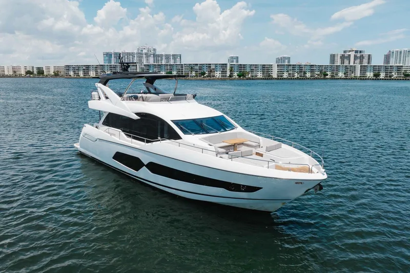 Slide: The Image of Luxurious 2022 Sunseeker 76 Yacht cruising on serene waters with cityscape backdrop. - 7