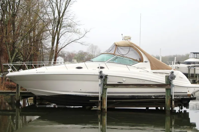 The Image of 2004 Sea Ray 340 Sundancer boat docked near trees on a cloudy day. - 0