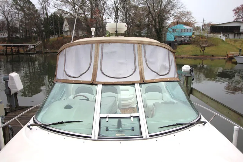 Slide: The Image of 2004 Sea Ray 340 Sundancer docked, featuring a covered cockpit and serene waterfront setting. - 12