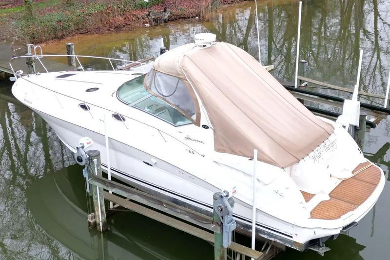 Slide: The Image of 2004 Sea Ray 340 Sundancer boat docked with beige cover, reflecting on calm water. - 8