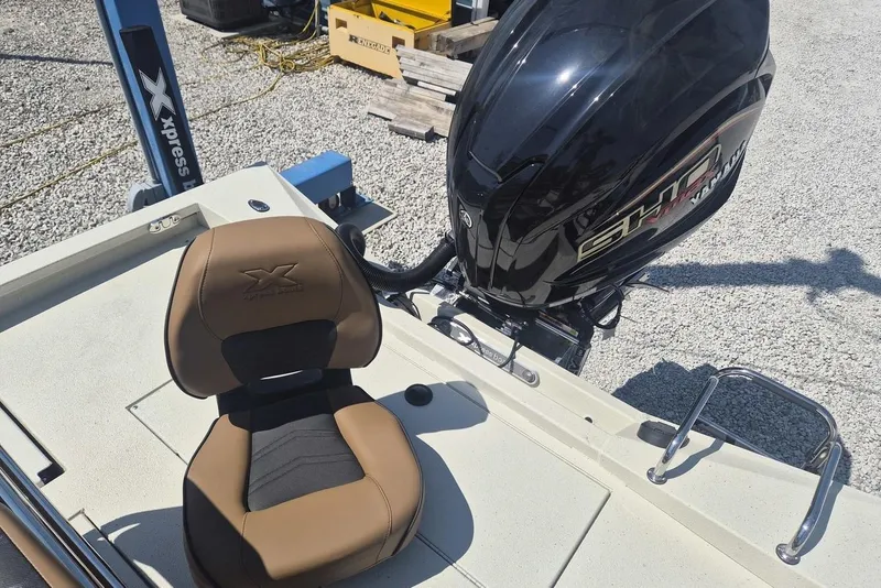 Slide: The Image of 2026 Xpress H24B Bay boat with Yamaha engine and brown seat on gravel surface. - 5