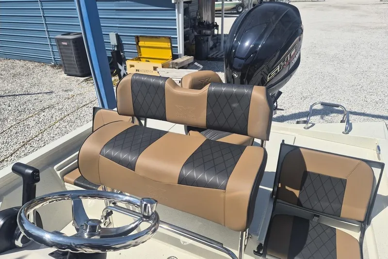 Slide: The Image of 2026 Xpress H24B Bay boat interior with tan and black seating, steering wheel, and motor. - 6