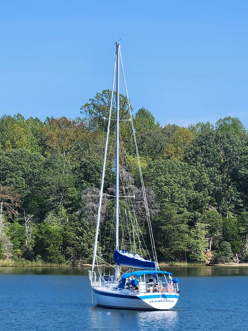 The Image of 1987 Wauquiez Centurion sailboat on calm water with forest backdrop. - 0