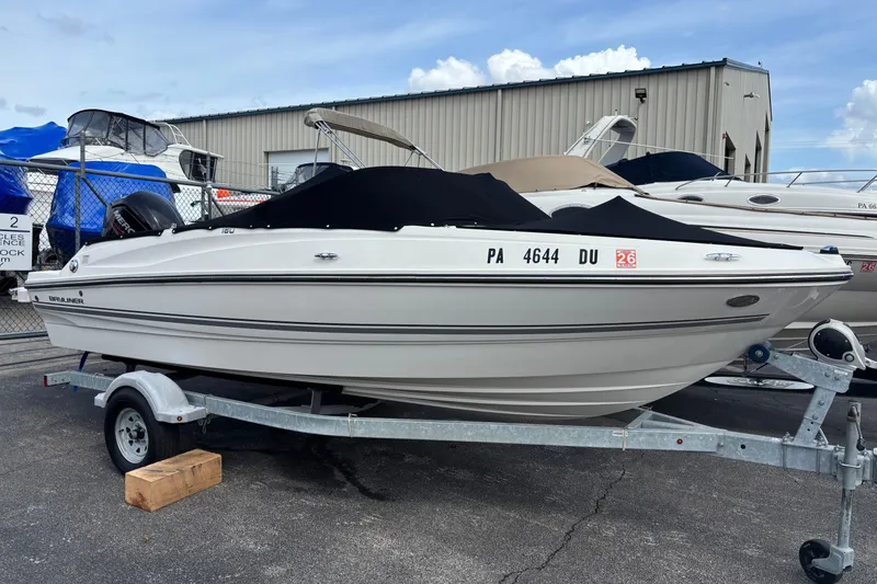 The Image of 2018 Bayliner 180 Bowrider boat on trailer, covered and parked outdoors. - 1