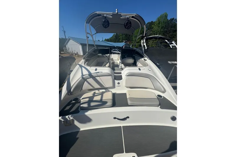 Slide: The Image of 2012 Yamaha Boats AR210 interior with seating and canopy, docked outdoors. - 10