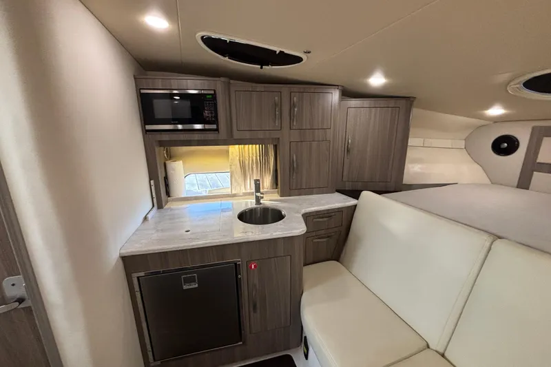 Slide: The Image of 2020 Regal 33 XO yacht interior with kitchenette, featuring microwave, sink, and seating area. - 13
