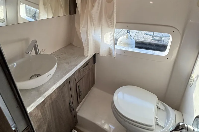 Slide: The Image of 2020 Regal 33 XO boat bathroom with sink, toilet, and window. - 8