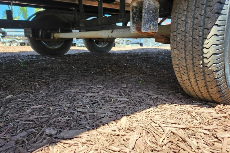 Slide: The Image of Underneath view of 2023 Sun Tracker Fishin' Barge 22 XP3 trailer wheels on mulch. - 34