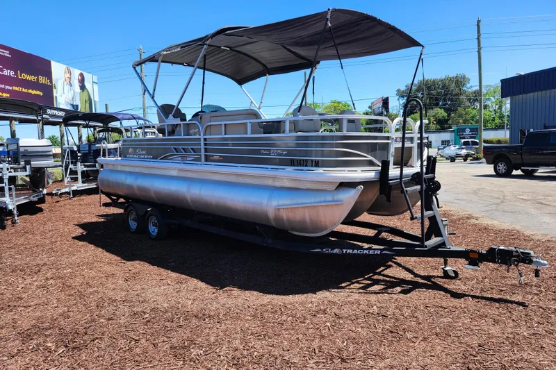 Slide: The Image of 2023 Sun Tracker Fishin' Barge 22 XP3 pontoon boat on trailer, parked outdoors. - 6
