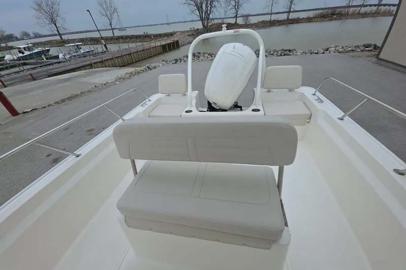 Slide: The Image of 2026 Boston Whaler 190 Montauk boat interior with seating and outboard motor, dockside view. - 10