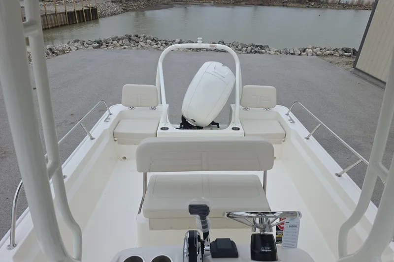 Slide: The Image of 2026 Boston Whaler 190 Montauk boat interior with seating and steering wheel, near water. - 16
