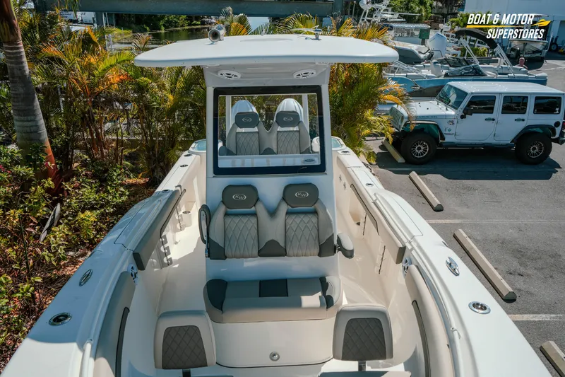 Slide: The Image of 2026 Key West 260 Center Console boat with sleek seating, parked near tropical foliage. - 27