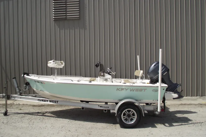 The Image of 2017 Key West 1520 Center Console boat on trailer, parked by a metal building. - 0