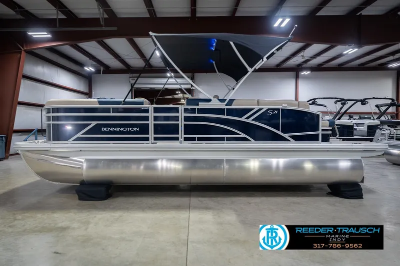 Slide: The Image of 2026 Bennington 21 SLJ pontoon boat in showroom, featuring sleek design and canopy. - 11