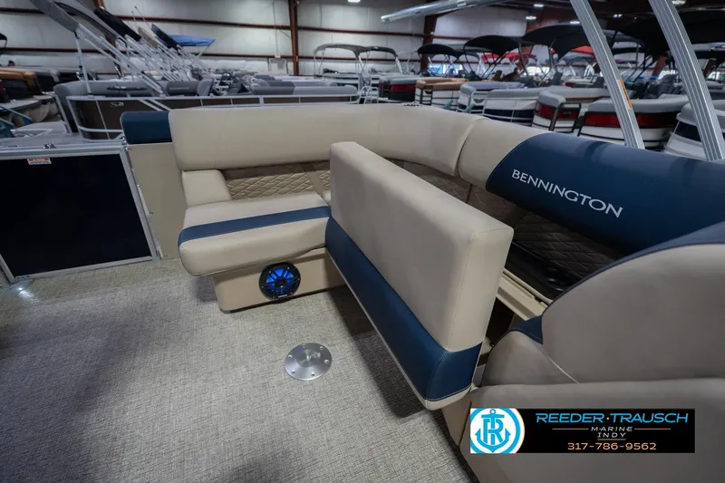 Slide: The Image of 2026 Bennington 21 SLJ pontoon boat interior with beige and blue seating in showroom. - 25