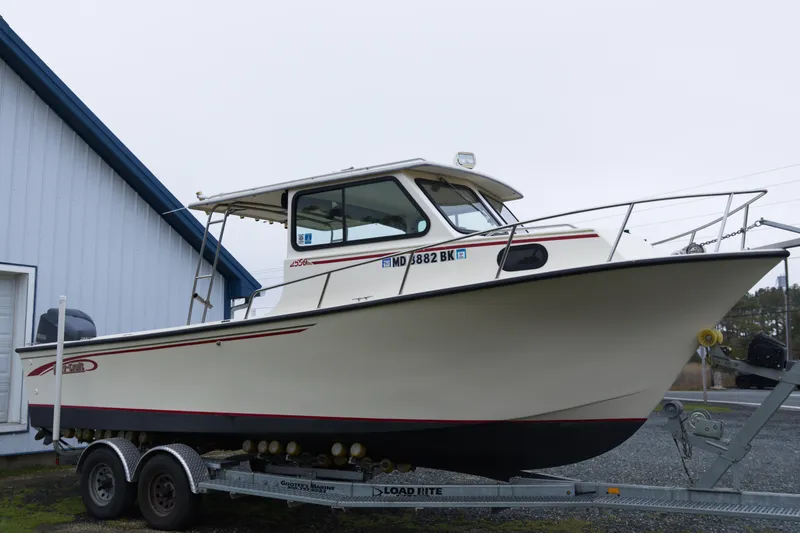 Slide: The Image of 2000 May-Craft 2550 Cabin boat on trailer near blue building. - 7