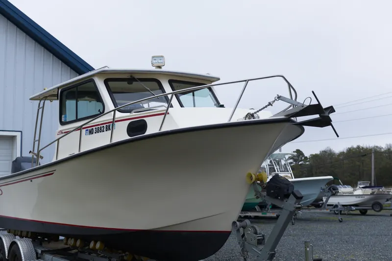 Slide: The Image of 2000 May-Craft 2550 Cabin boat on trailer, parked near a building. - 8