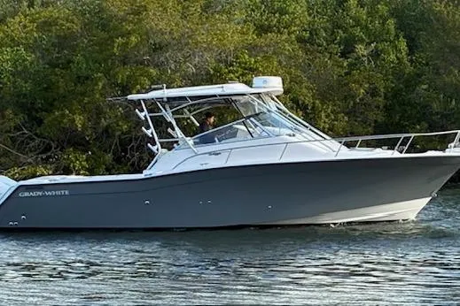 The Image of 2003 Grady-White Express 330 boat cruising on a calm river near lush greenery. - 0