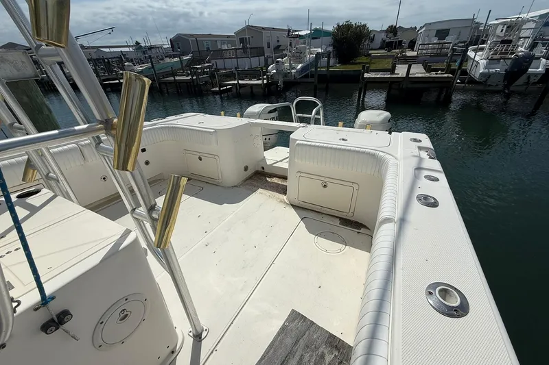 Slide: The Image of 2005 World Cat 330 TE boat docked at marina, showcasing spacious deck and fishing rod holders. - 12